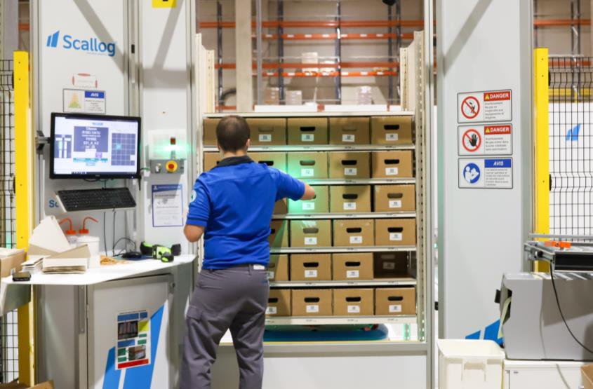 Operator at a Scallog goods-to-person picking station with pick-to-light guidance